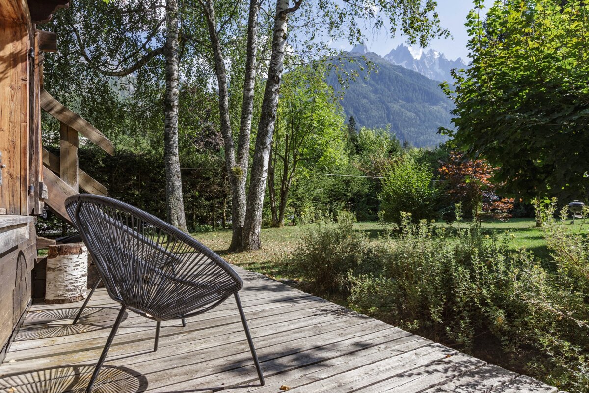 A chair sits on a wooden deck with mountains in the background