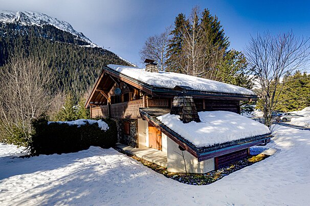 A snowy cabin with a mountain in the background