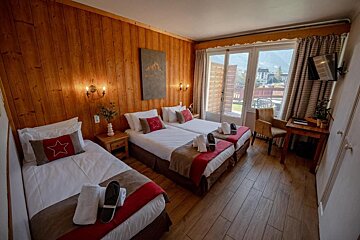 A hotel room with three beds and a painting on the wall