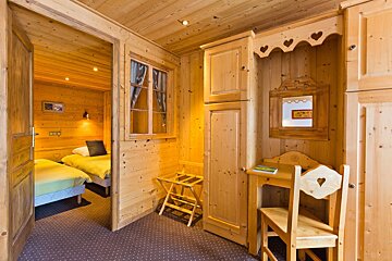 A wooden room with two beds and a desk