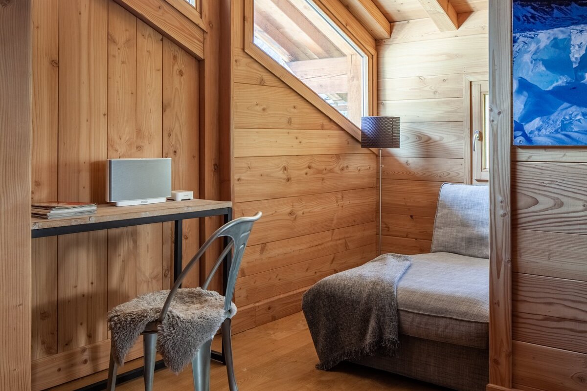 A chair sits next to a desk with a bose speaker on it