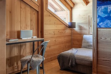 A chair sits next to a desk with a bose speaker on it