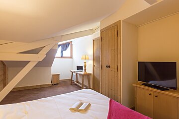 A bedroom with a bed and a flat screen tv