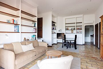 A living room with a couch a chair and a table with a book on the shelf that says happiness