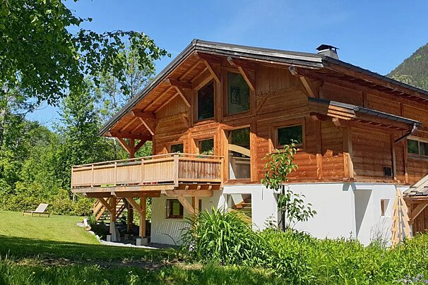 A large wooden house with a balcony in the backyard