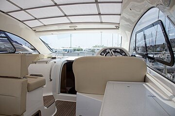 The inside of a boat with a steering wheel and seats