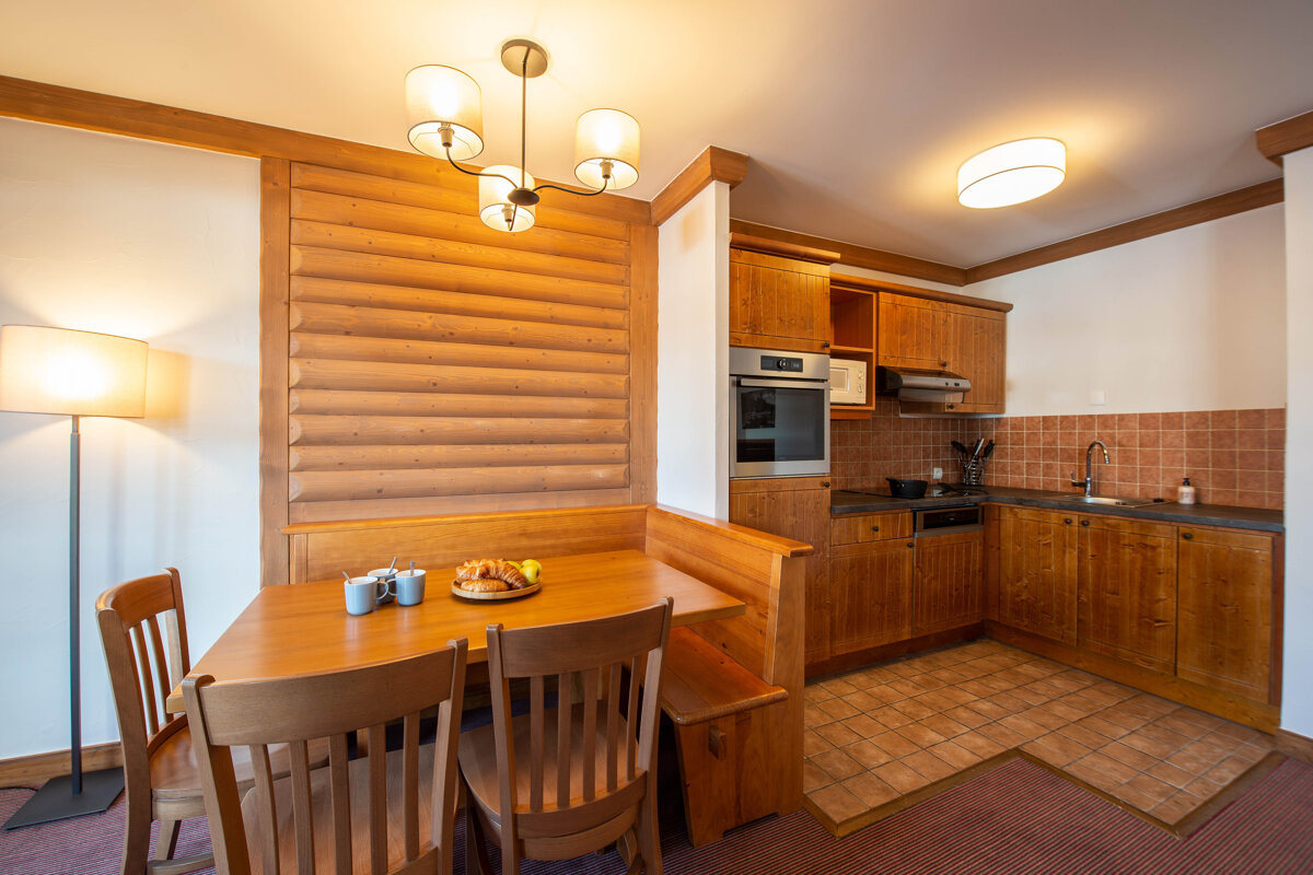 A kitchen with a table and chairs and a clock on the wall that says 10:08