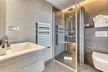 A bathroom with a walk in shower and a sink