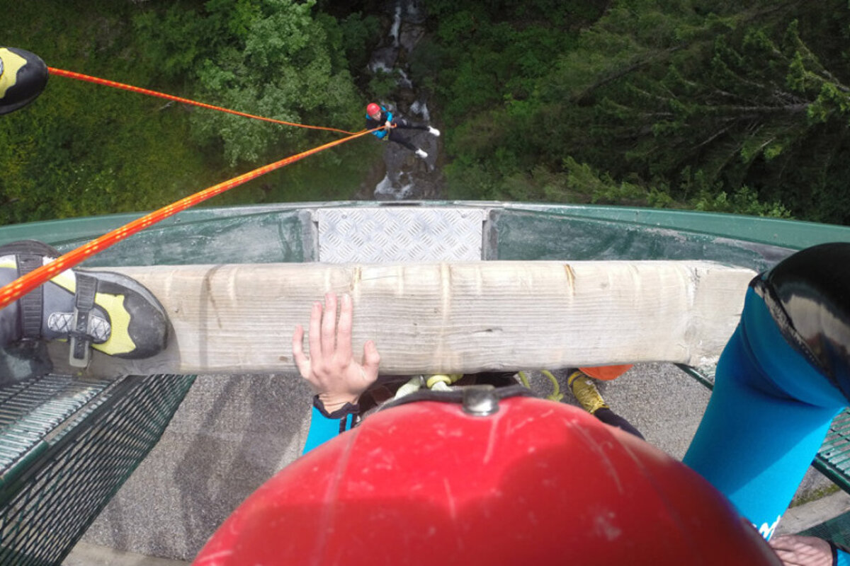 canyoneers rapelling off a bridge