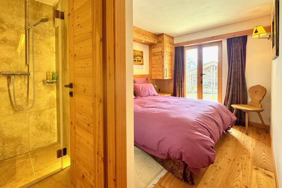 A bedroom with a purple comforter and a wooden chair