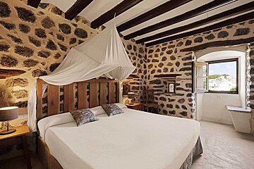 A bedroom with a canopy bed and a stone wall