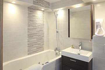 A bathroom with a bathtub sink and mirror