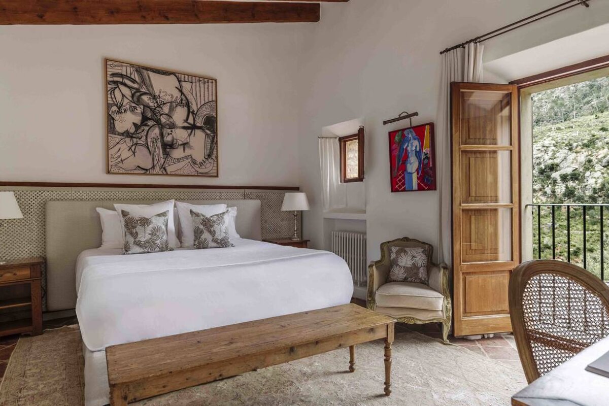 A bedroom with a painting on the wall above the bed