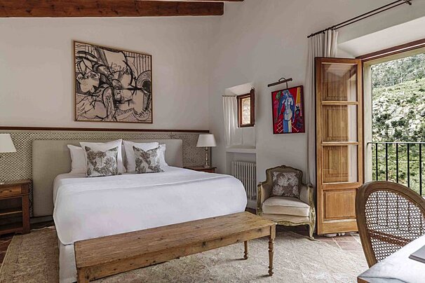 A bedroom with a painting on the wall above the bed