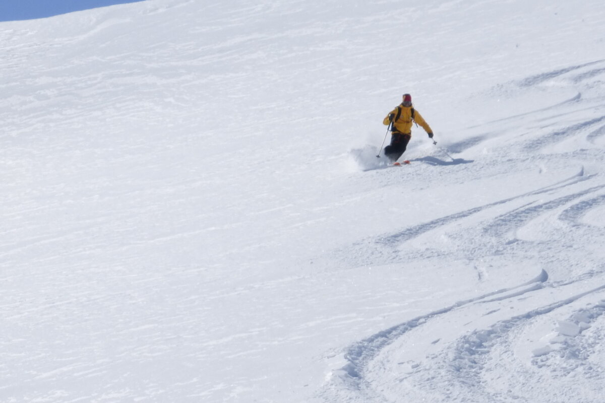 a man in a yellow ski jacket off piste