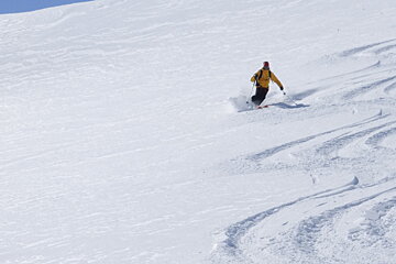 a man in a yellow ski jacket off piste