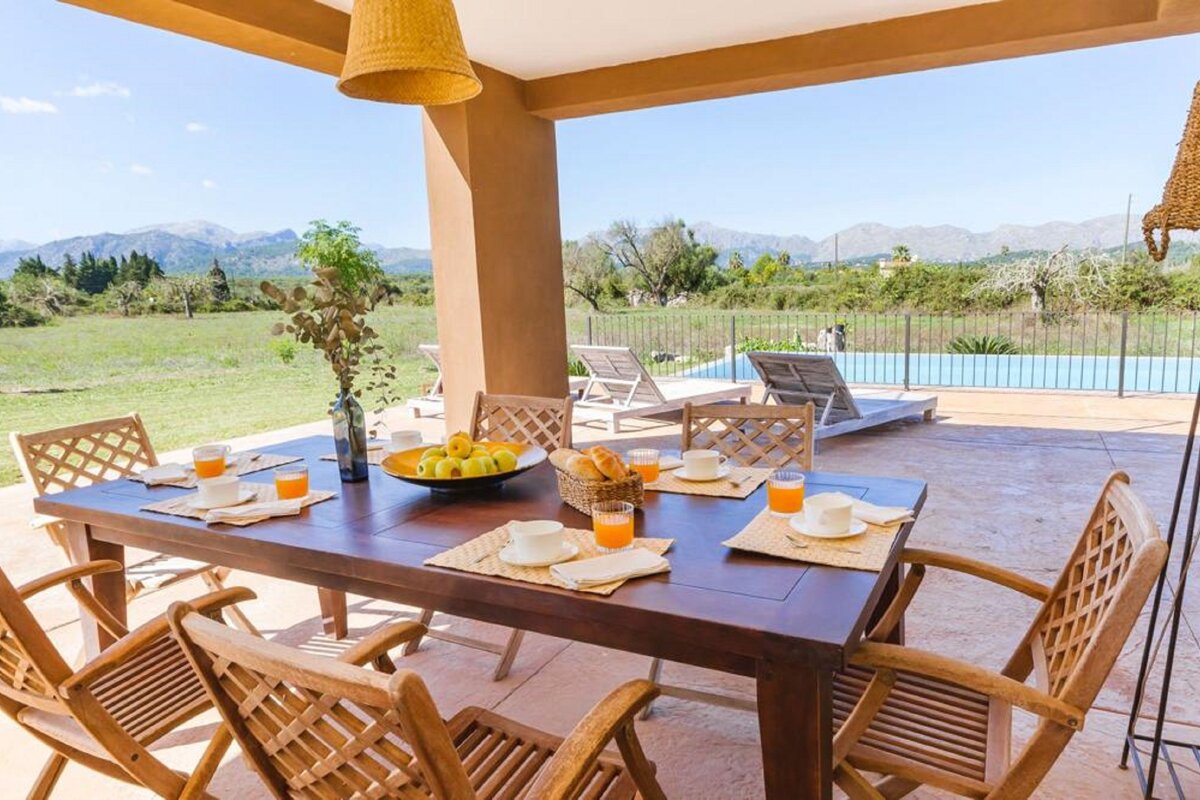 A table and chairs on a patio with mountains in the background