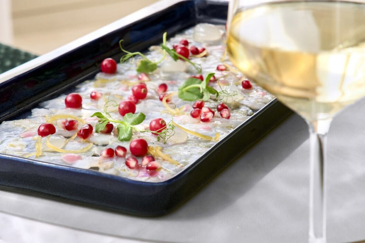 A tray of food next to a glass of wine