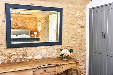 A large mirror hangs above a desk in a bedroom