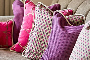 A couch with pink and purple pillows on it