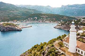 A lighthouse sits on a hill overlooking a body of water