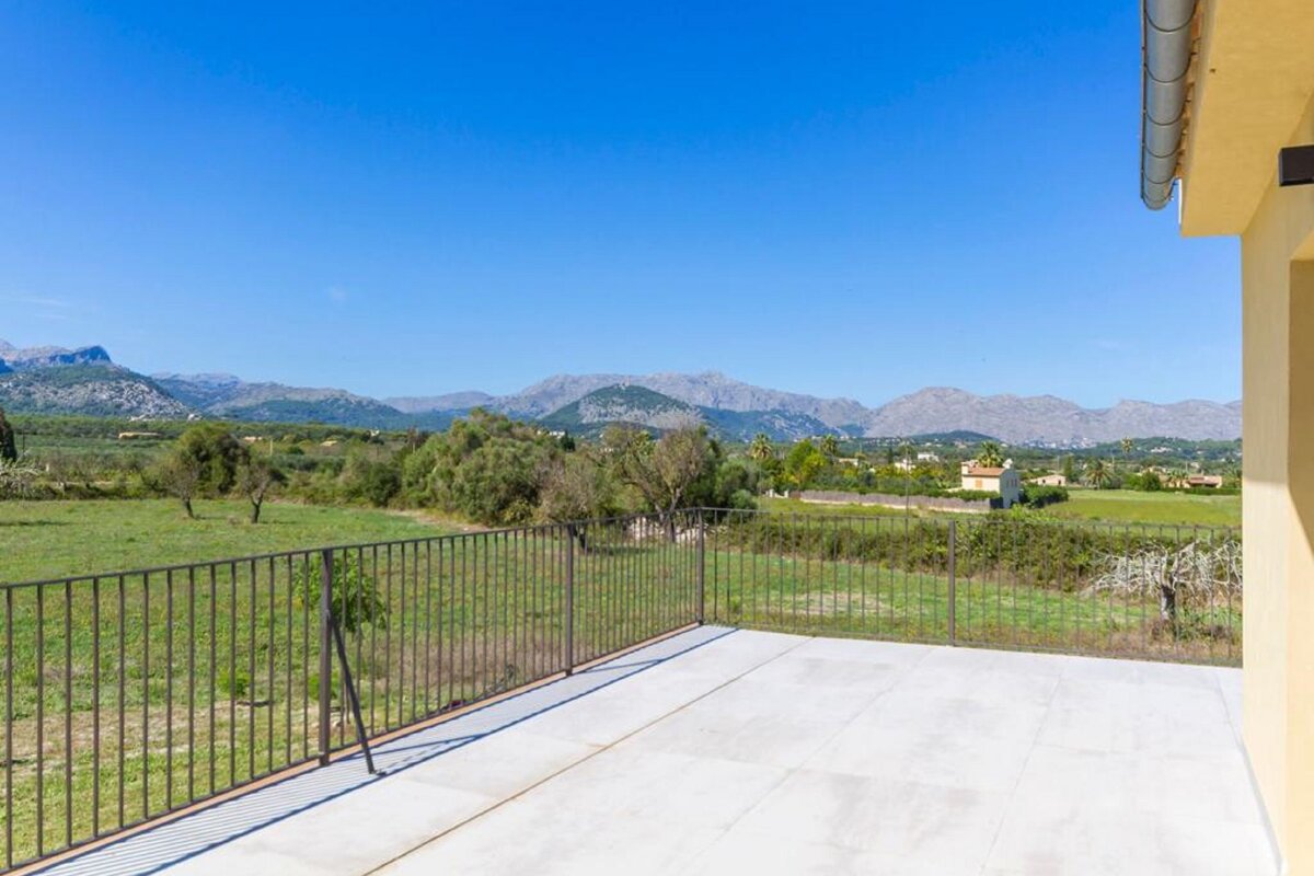 A balcony overlooking a field with mountains in the background