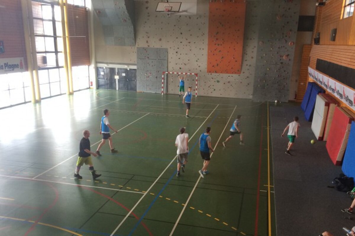 A group of people are playing basketball in a gym with a sign that says la plage