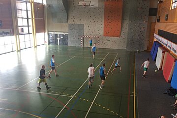 A group of people are playing basketball in a gym with a sign that says la plage