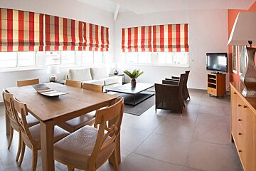 A living room with red and white striped roman shades