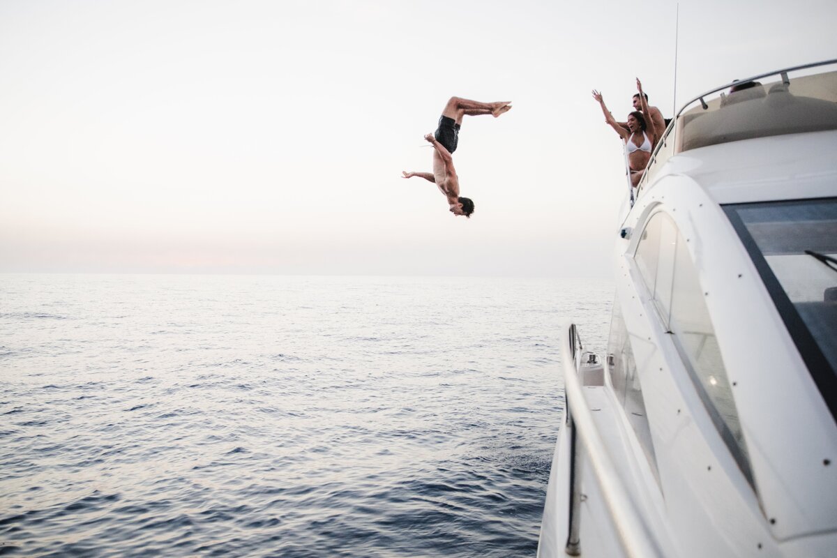 A man is jumping off a boat into the ocean