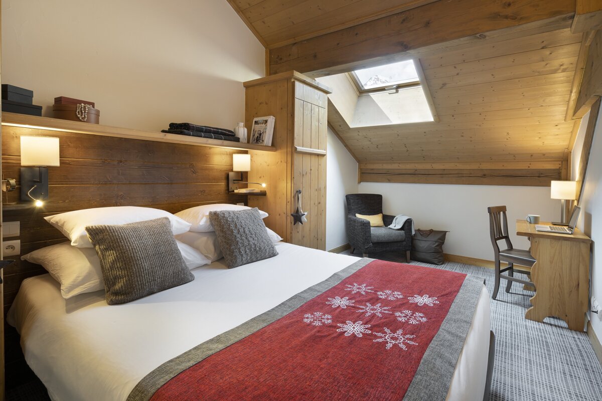 A bedroom with a bed a chair and a desk