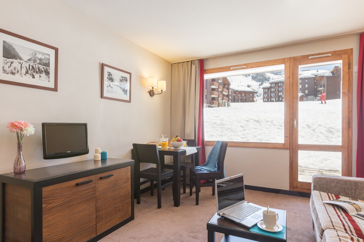 A living room with a table and chairs and a tv