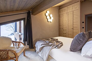A bedroom with a bed a chair and a window