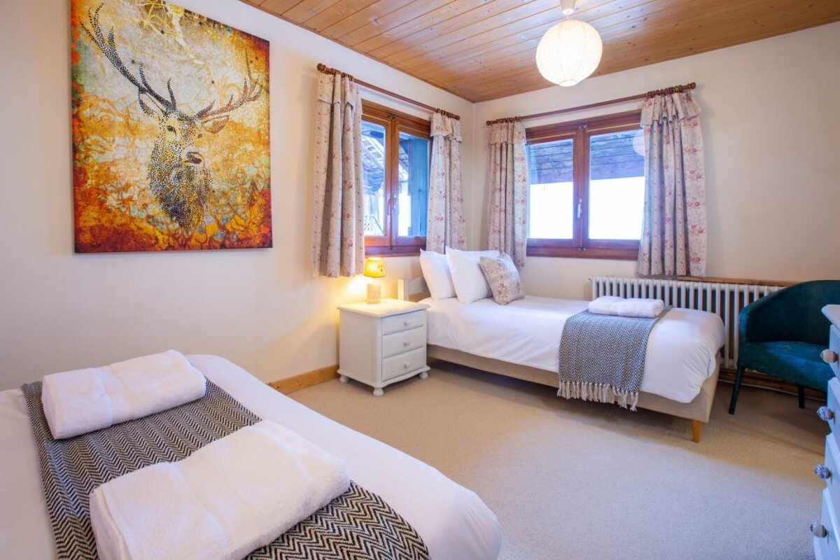 A bedroom with two beds and a painting of a deer on the wall