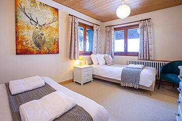 A bedroom with two beds and a painting of a deer on the wall