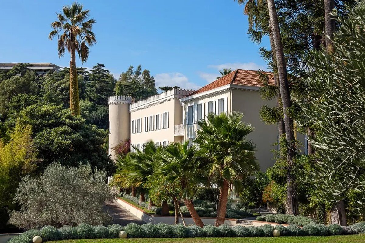 A large white building surrounded by palm trees and bushes