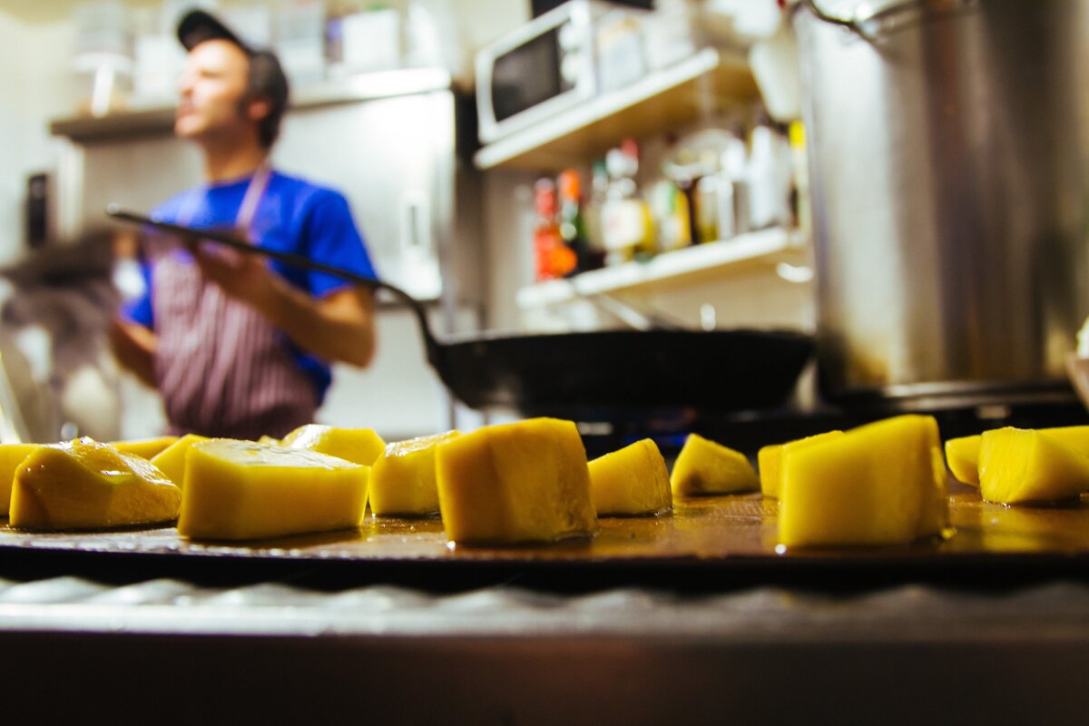 A man in a blue shirt is cooking in a kitchen