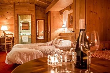 A bottle of wine sits on a table in front of a bed