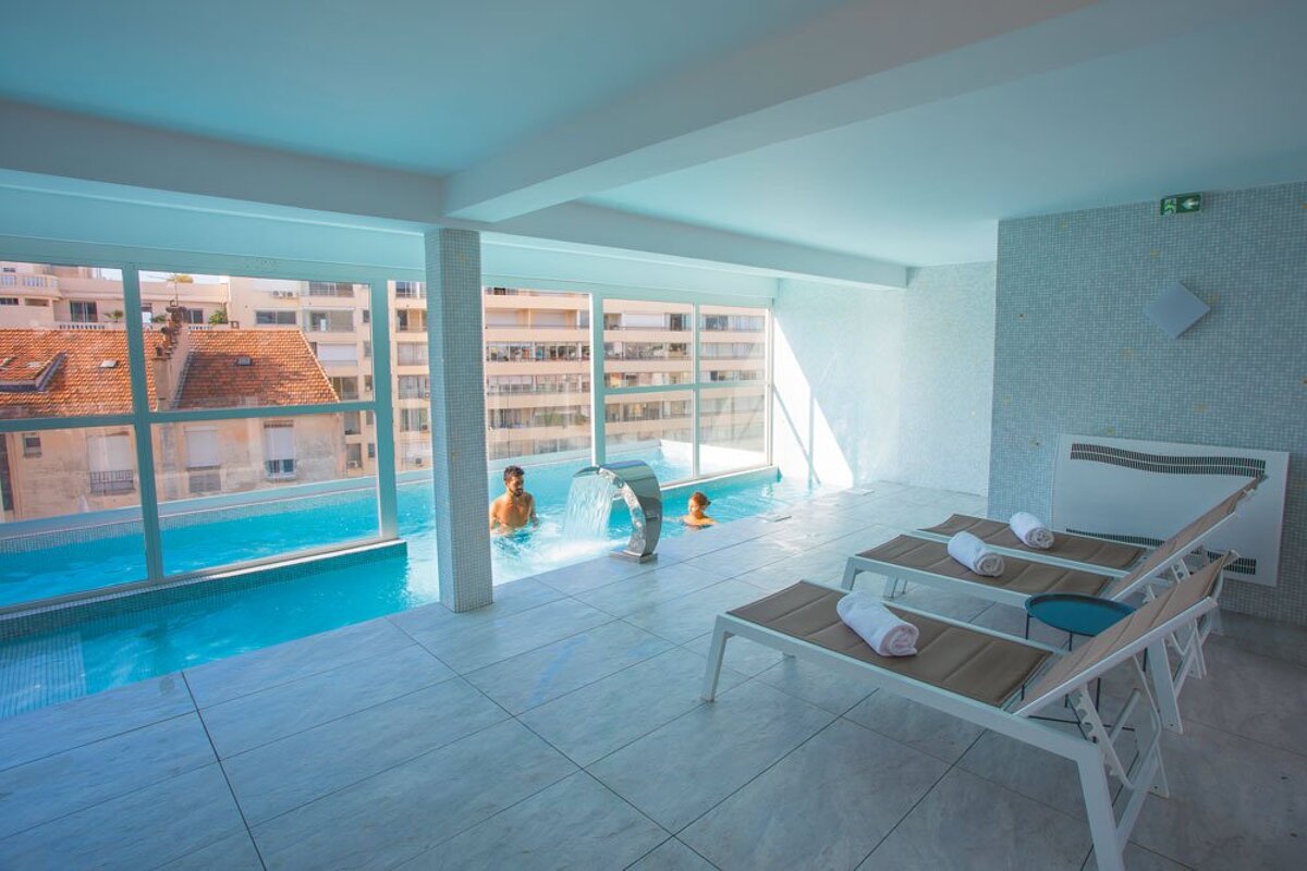A man is swimming in a pool with a waterfall