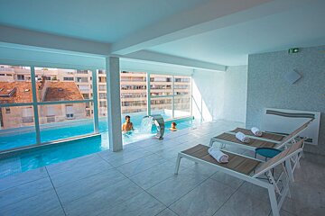 A man is swimming in a pool with a waterfall