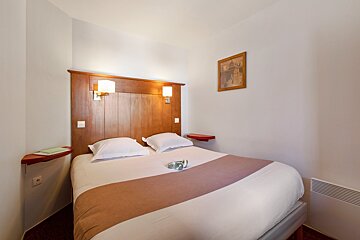 A hotel room with a bed and a picture on the wall