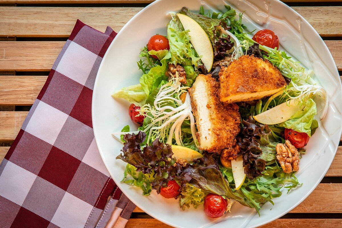 A white plate topped with a salad of lettuce tomatoes and cheese