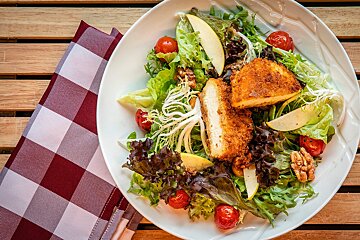A white plate topped with a salad of lettuce tomatoes and cheese