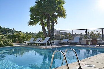 A large swimming pool surrounded by chairs and palm trees