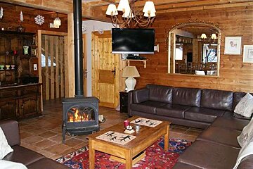 A living room with a couch , coffee table , television and fireplace