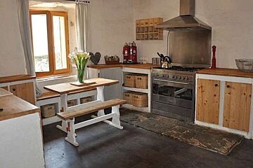 A kitchen with wooden cabinets , a stove , a table and a bench