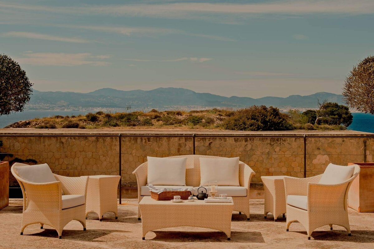A patio with a couch and chairs with mountains in the background