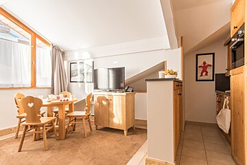 A living room with a table and chairs and a tv