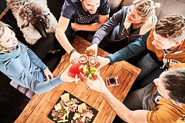 A group of people toasting with drinks on a wooden table