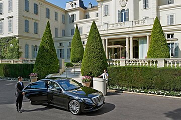 A black mercedes is parked in front of a large building